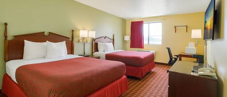 A hotel room with two beds, a desk, a chair, a TV, and a window with curtains.