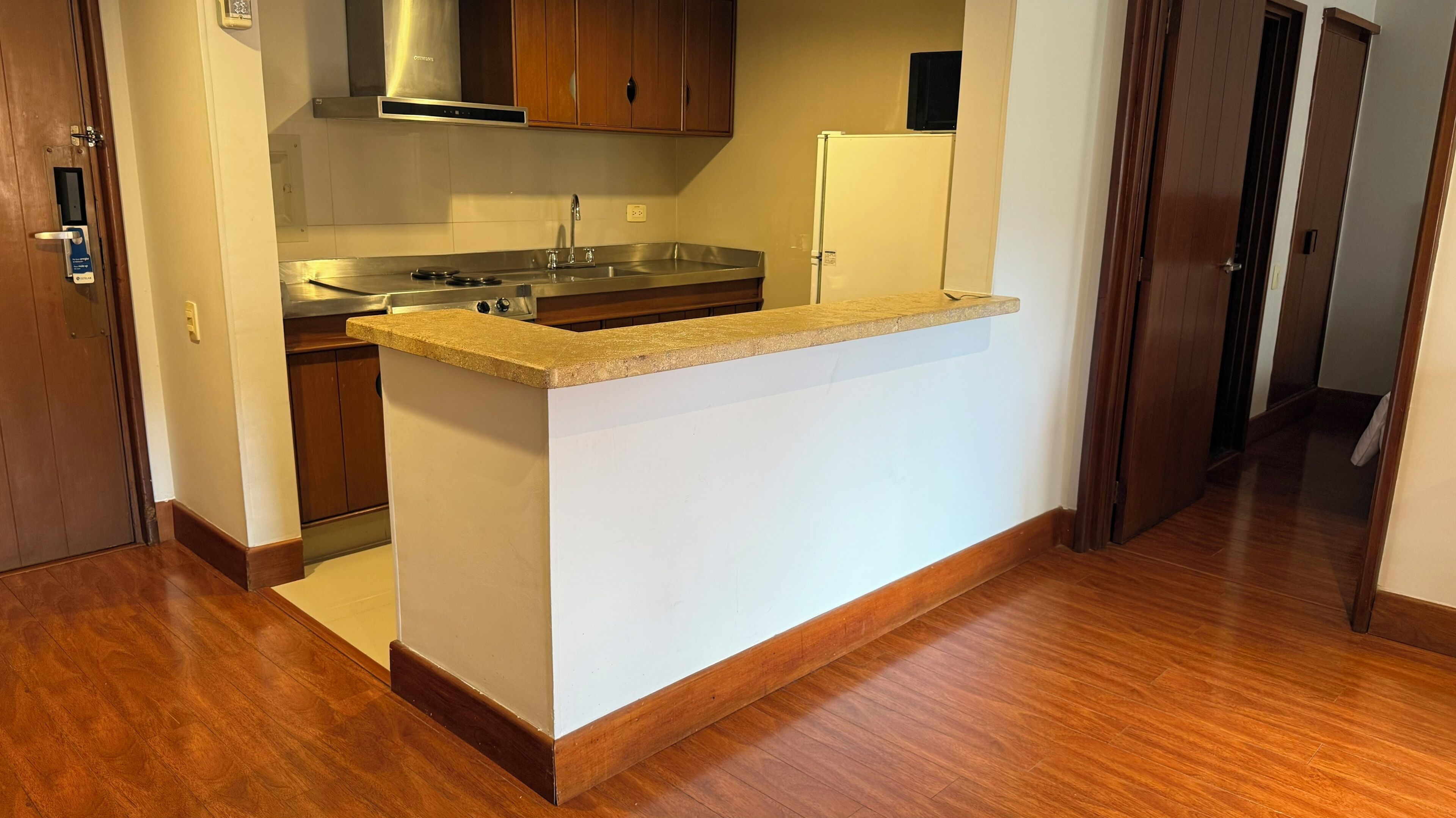 Una cocina con armarios de madera, un lavamanos de acero inoxidable y un refrigerador blanco.