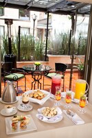 Una mesa de desayuno dispuesta con diferentes alimentos, bebidas y una jarra de café.