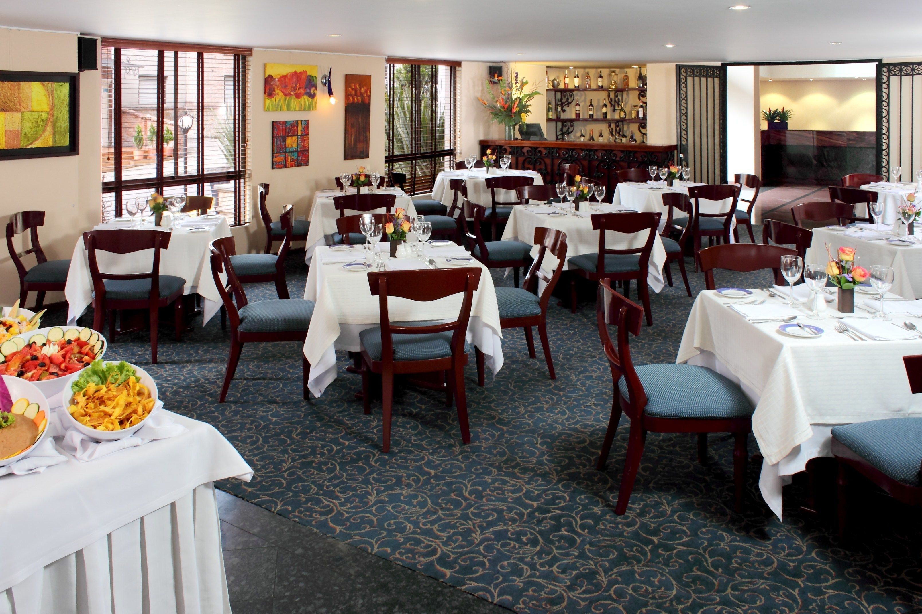 Een restaurant met meerdere tafels en stoelen, elk voorzien van een wit tafelkleed en glazen.
