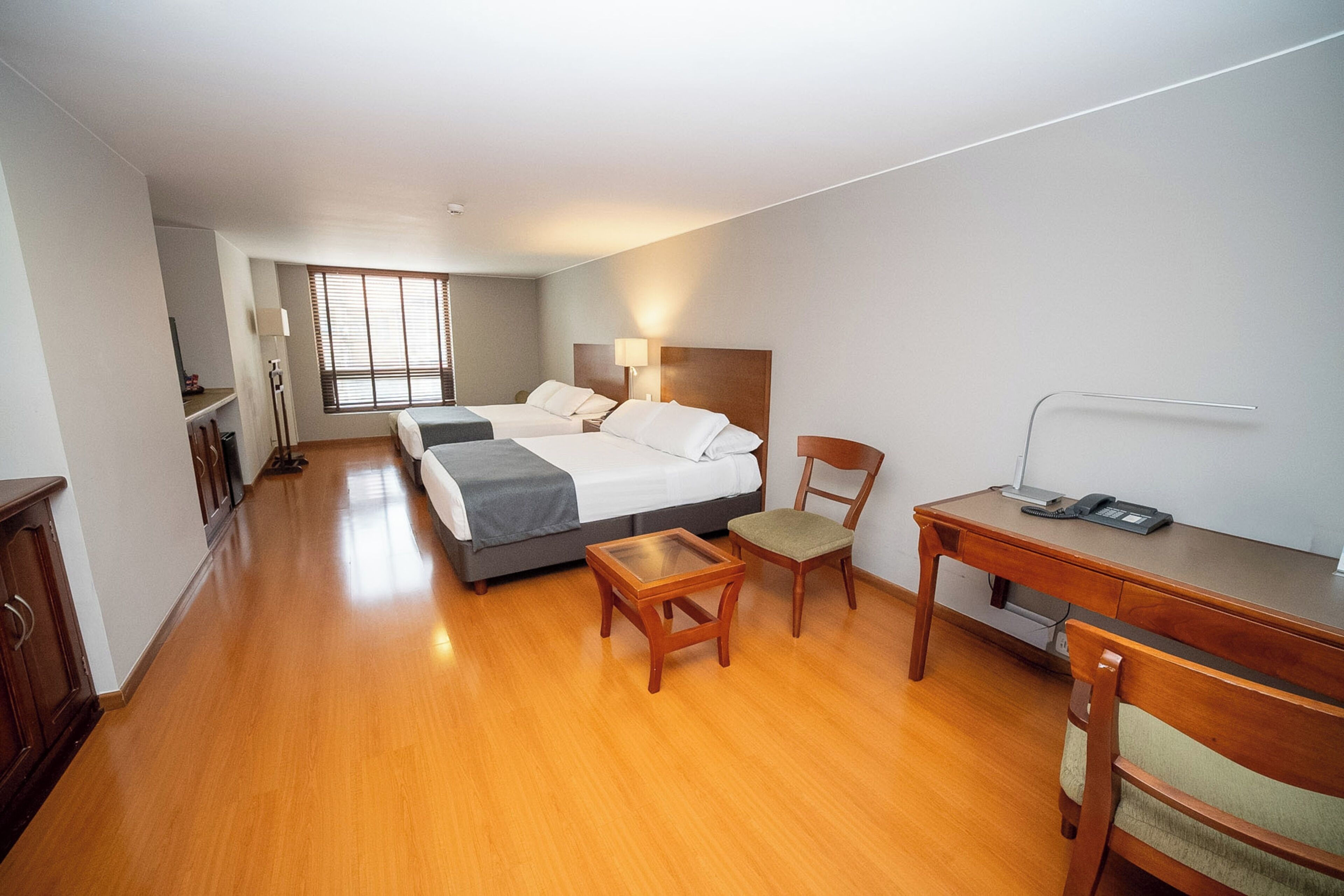 Una habitación de hotel con una cama, un escritorio, una silla, una lámpara y un teléfono.