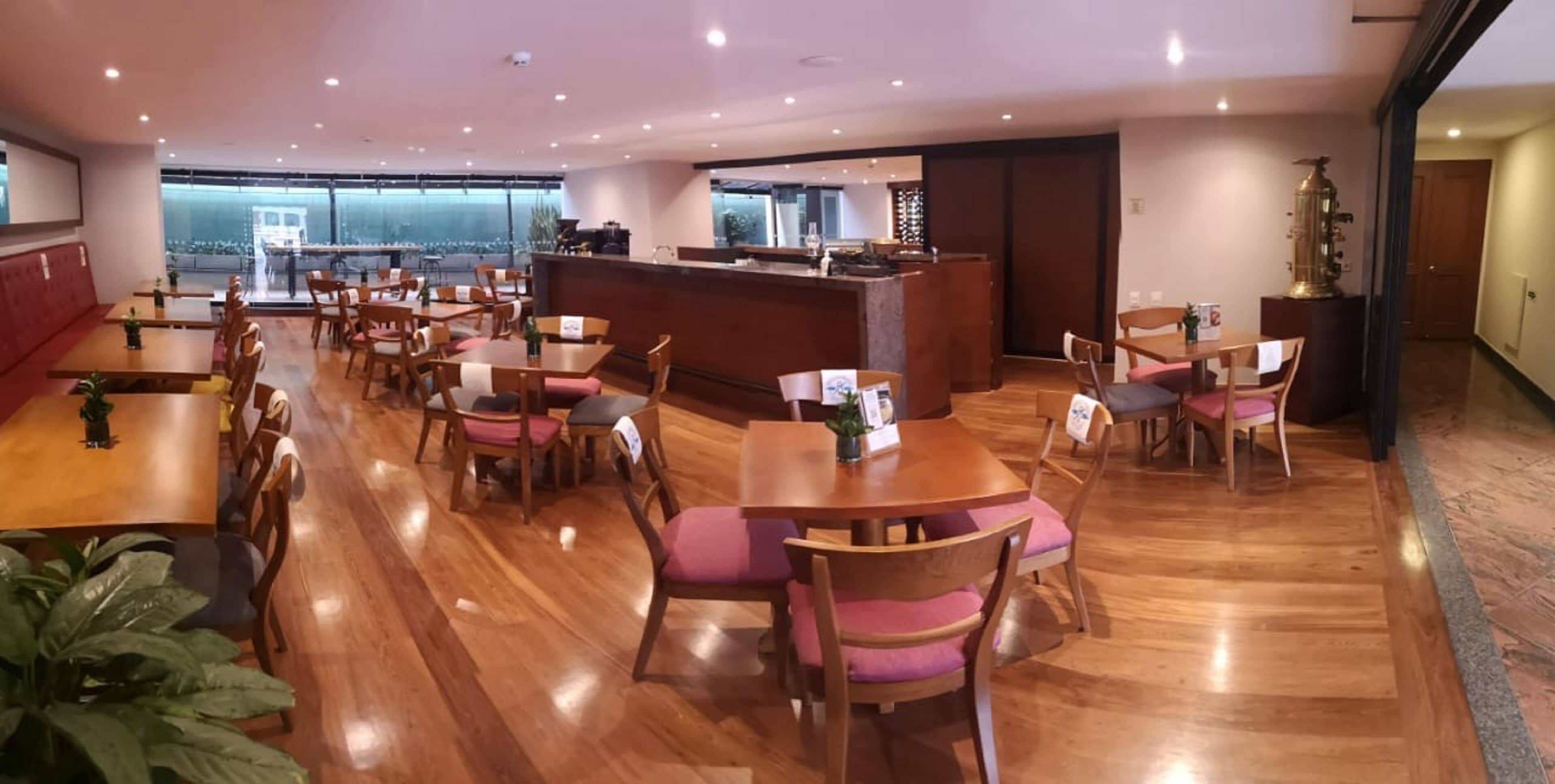 Un restaurant spacieux avec des tables et des chaises en bois, un bar central et de grandes fenêtres offrant une vue panoramique.