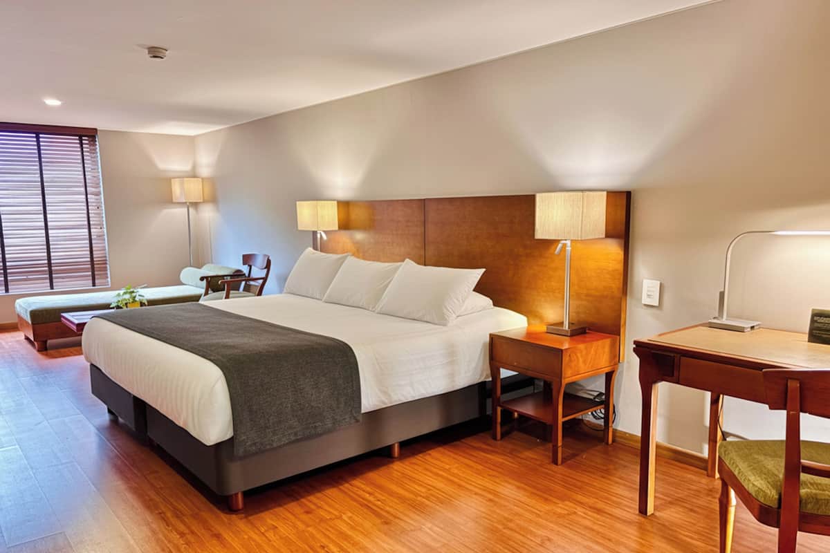 Una habitación de hotel moderna con una cama grande, un escritorio, una silla y una pequeña mesa.