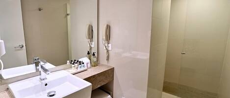 A modern bathroom with two sinks, a mirror, a toilet, and a glass-enclosed shower.