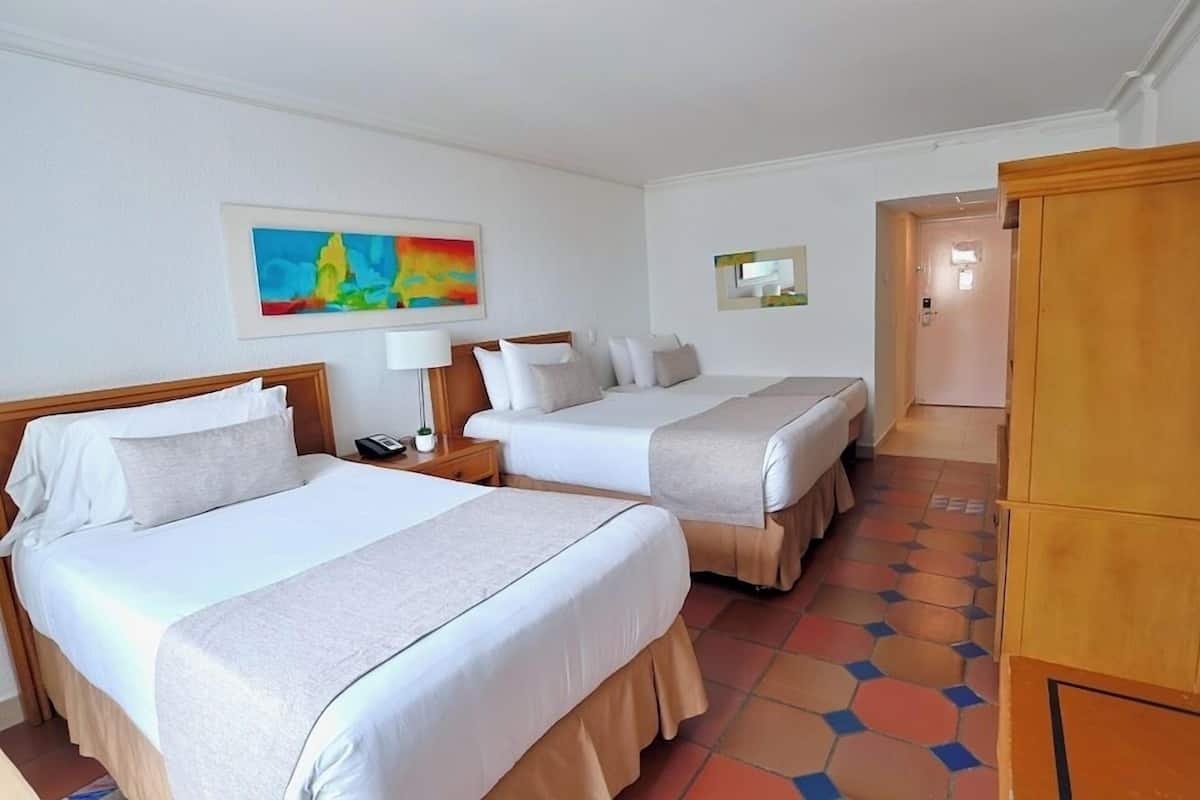 Een hotelkamer met twee bedden, een schilderij aan de muur, een spiegel en een houten kledingkast.