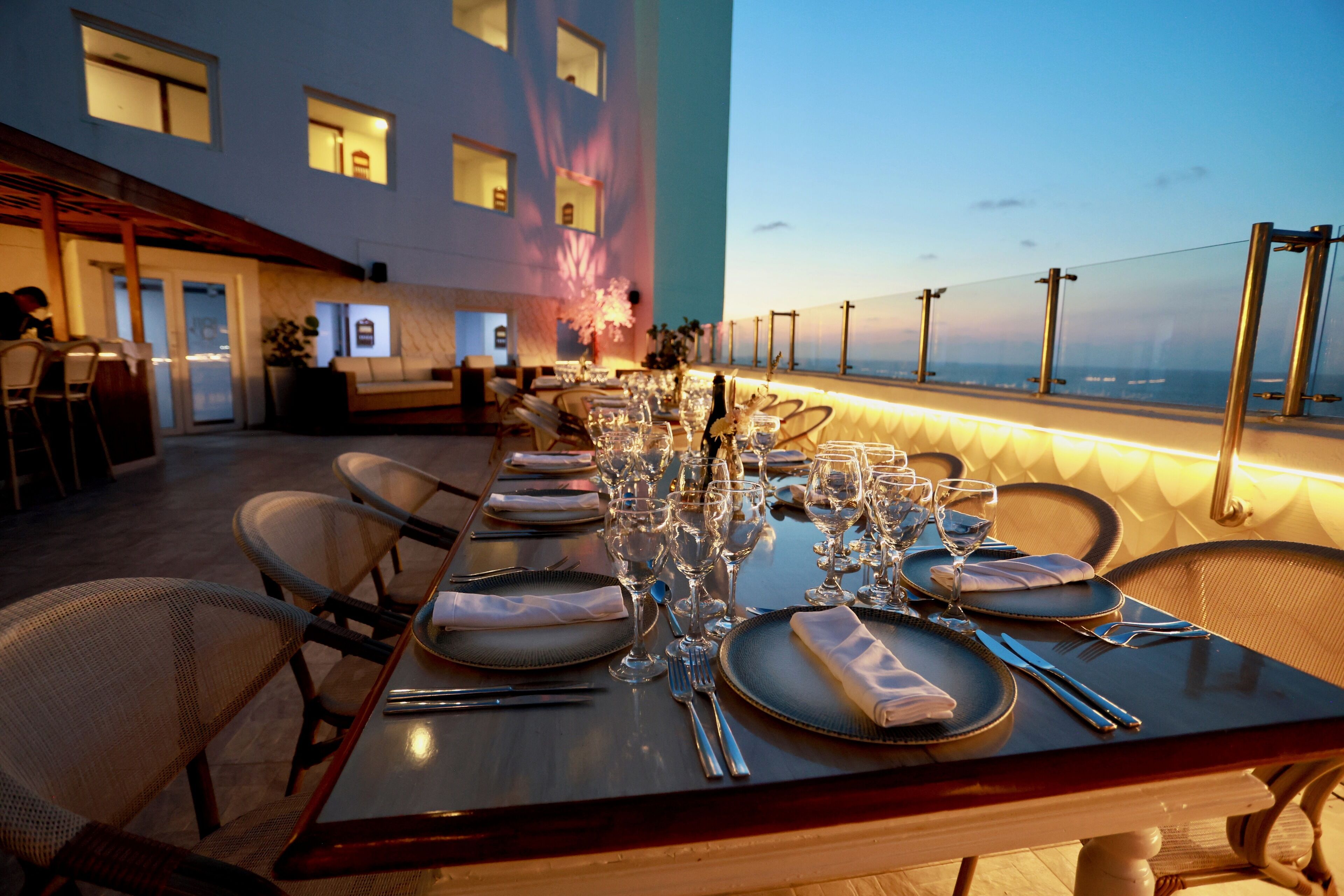 Ein Esszimmer mit Tisch, mehreren Stühlen und Meerblick, im Hintergrund ein Gebäude mit Fenstern.