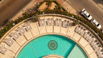 Een buitenzwembad, parasols bij het zwembad en ligstoelen