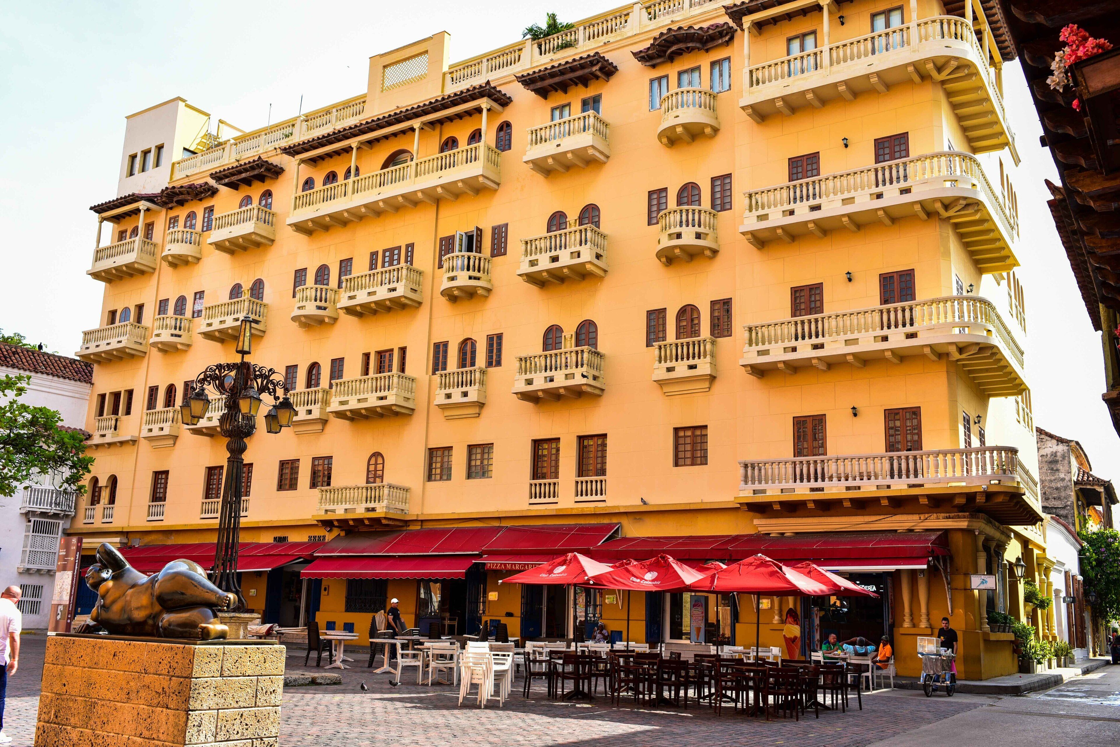 A multi-story building with balconies, outdoor seating, and a statue.