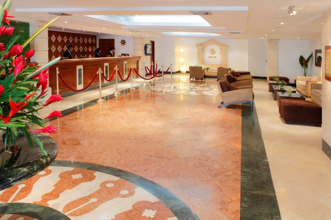 A hotel lobby with a reception desk, seating area, and a decorative floor pattern.
