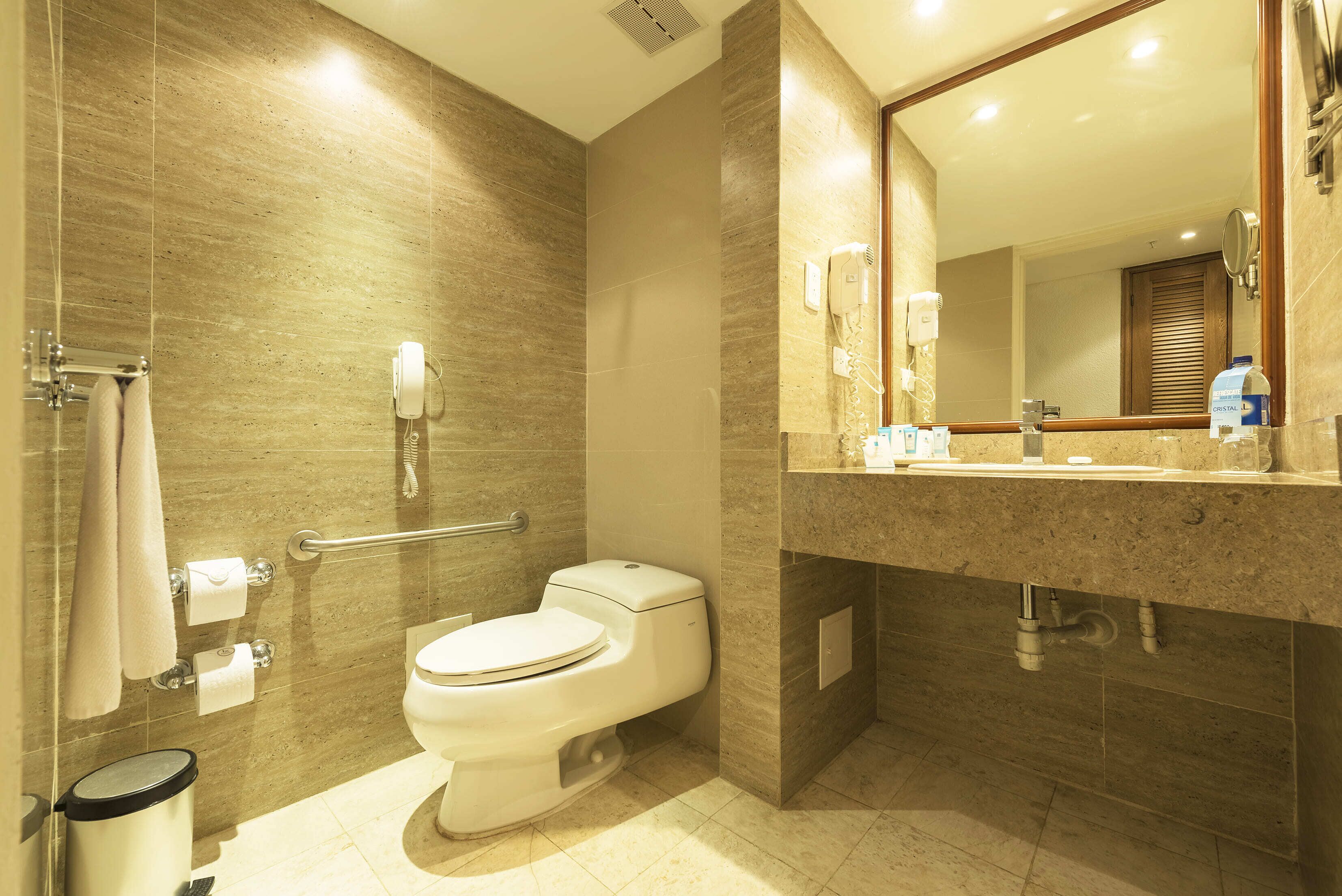 A modern bathroom with a toilet, hand dryer, and a mirror above the sink.