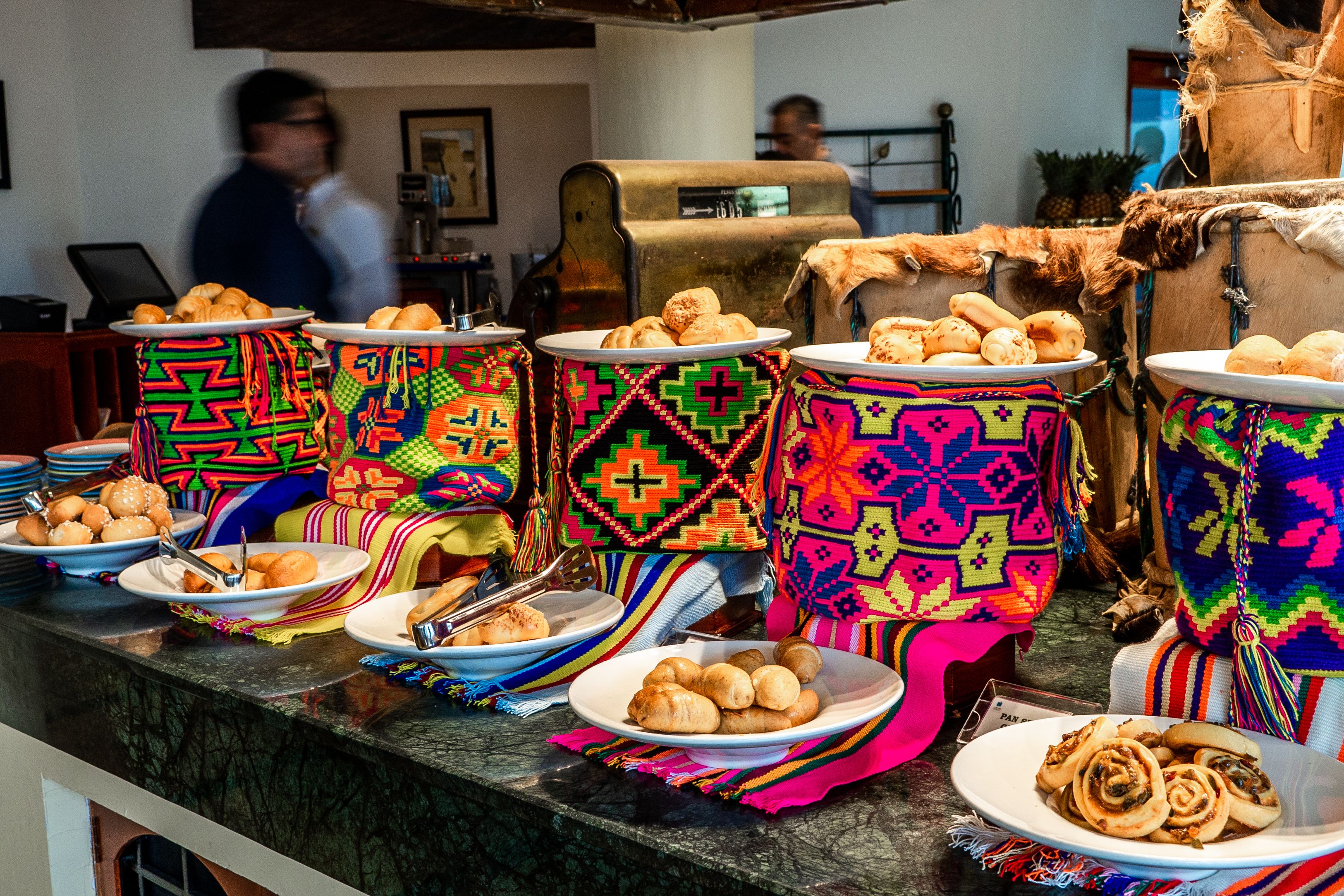 A buffet with colorful woven placemats and plates of pastries.