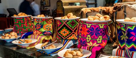 A buffet with colorful woven placemats and plates of pastries.