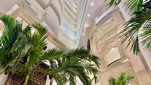 Un atrio de techos altos con diseño moderno, que presenta un espacio central abierto y elementos decorativos como un techo de cristal y paredes de piedra.