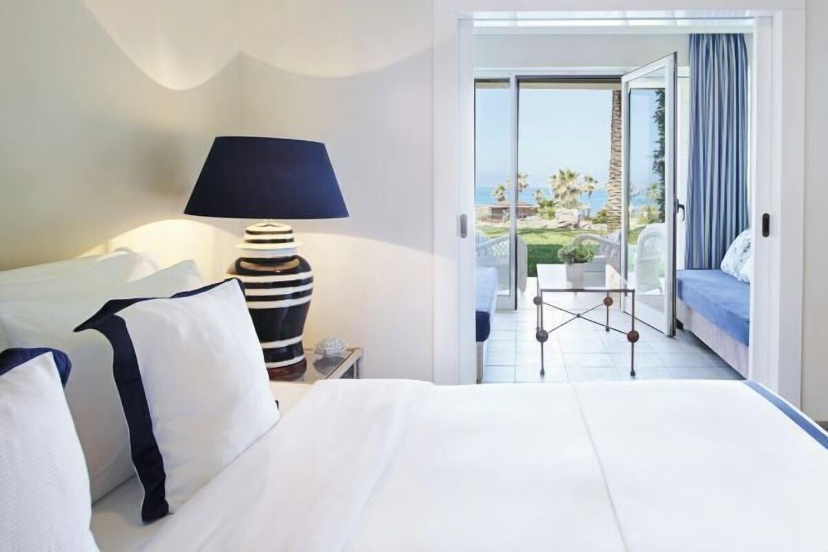 A hotel room with a bed, a lamp, and a view of the outdoors.