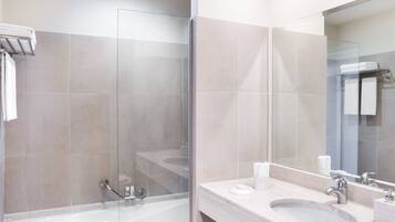 Un baño moderno con ducha de vidrio, tocador con lavamanos y un espejo grande.
