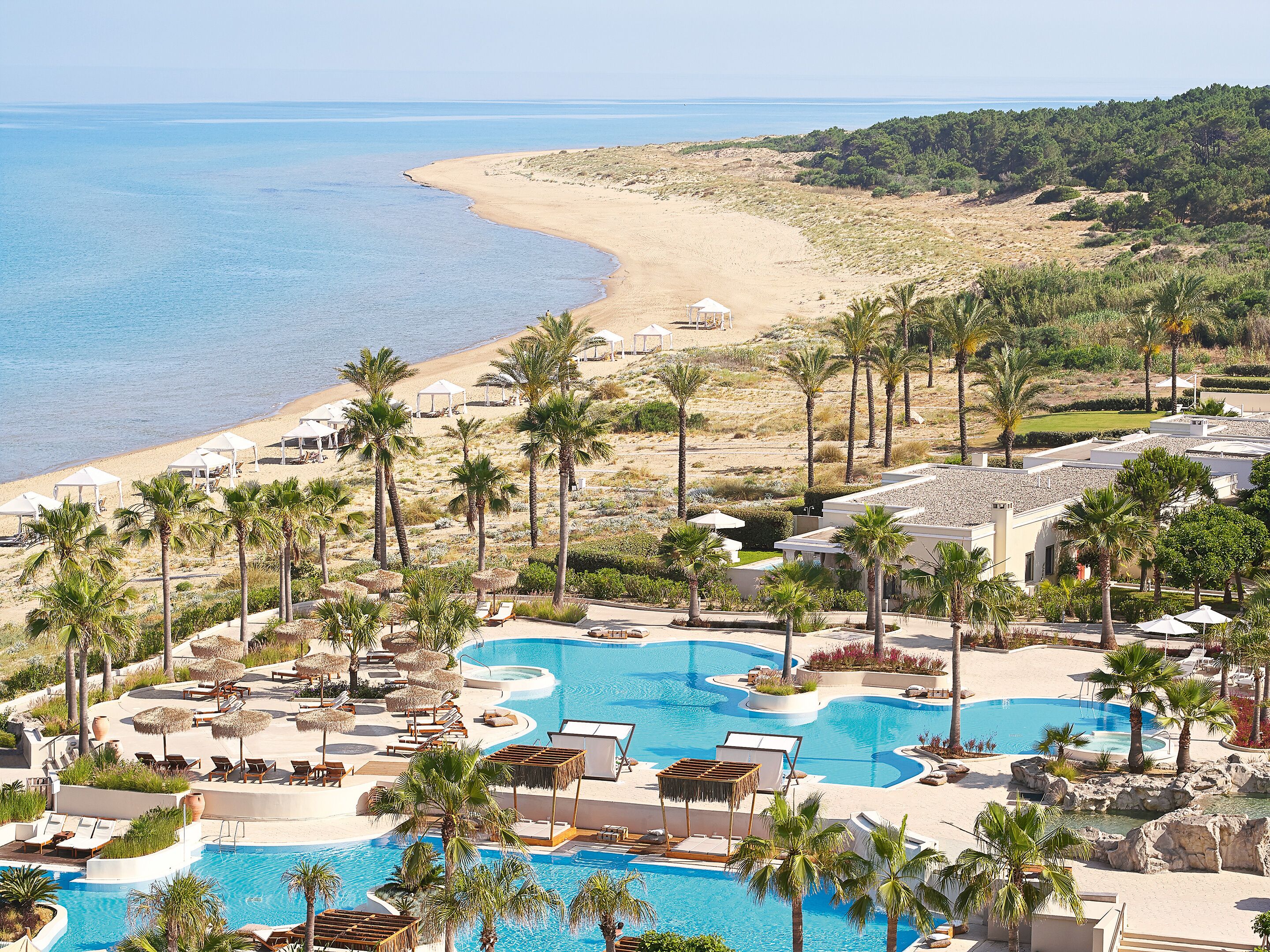 A resort with multiple swimming pools, beach access, and palm trees.