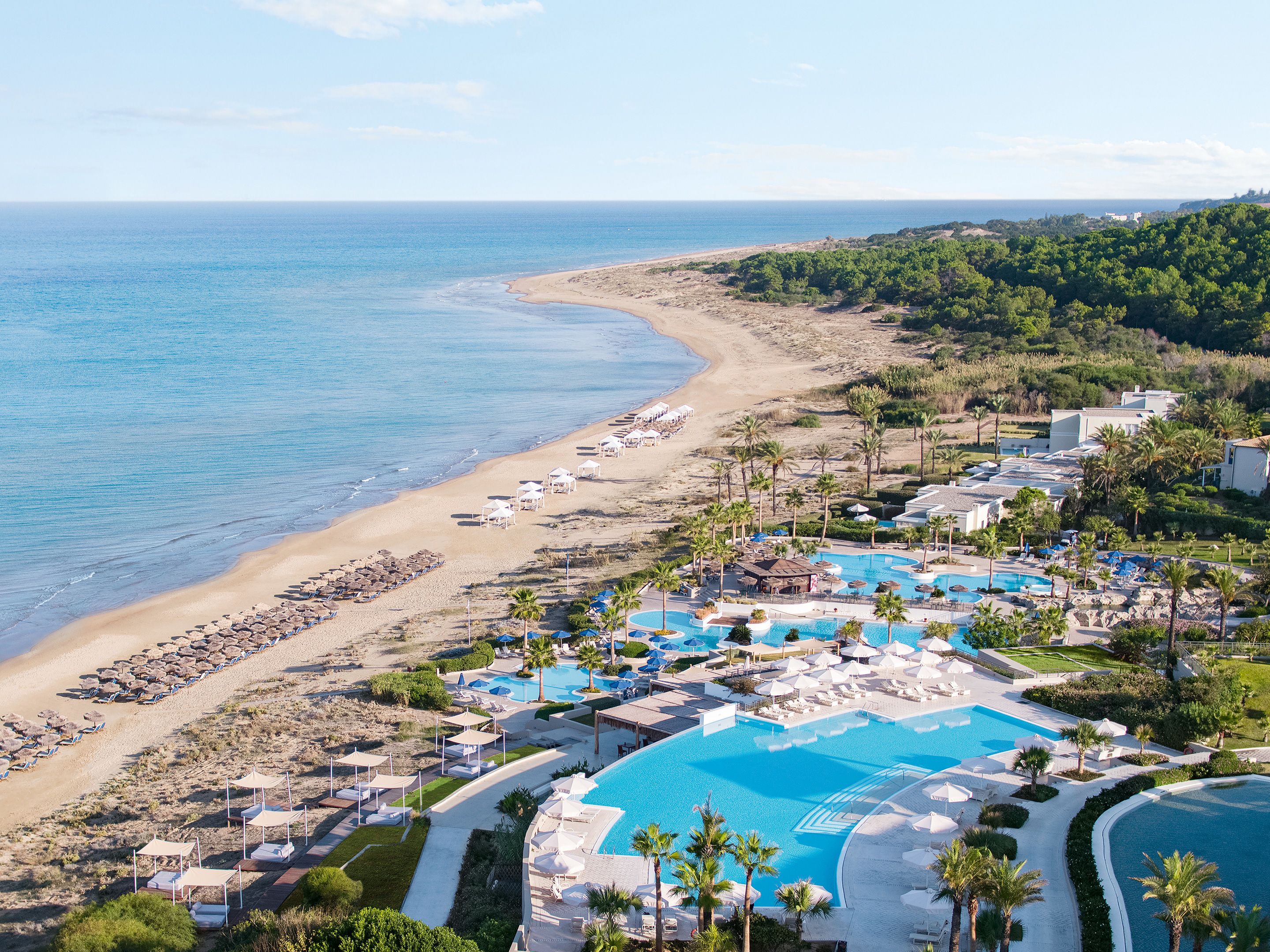 A resort with a large pool, beach, and ocean view.