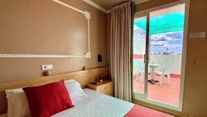 A hotel room with a bed, a nightstand, a window with curtains, and a view of the outside. - Hotel Piccadilly Sitges (Sitges)