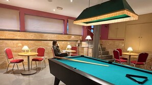 A pool table with chairs around it, a staircase, and a room with a red wall and a large window. - Hotel Piccadilly Sitges (Sitges)