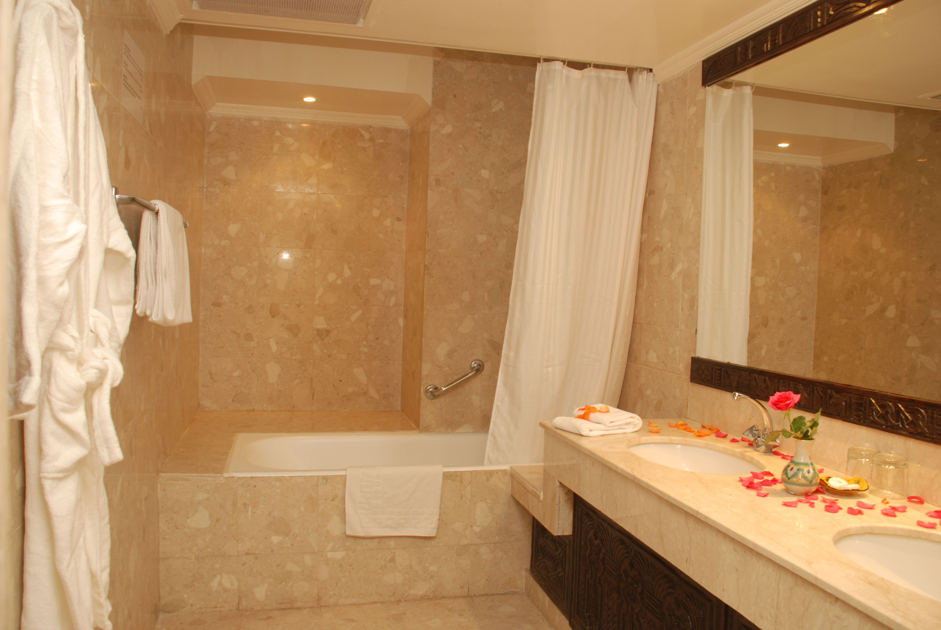 A bathroom with a bathtub, a shower, a vanity with a mirror, and a towel rack.