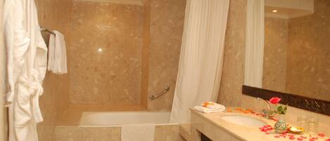 A bathroom with a bathtub, a shower, a vanity with a mirror, and a towel rack.