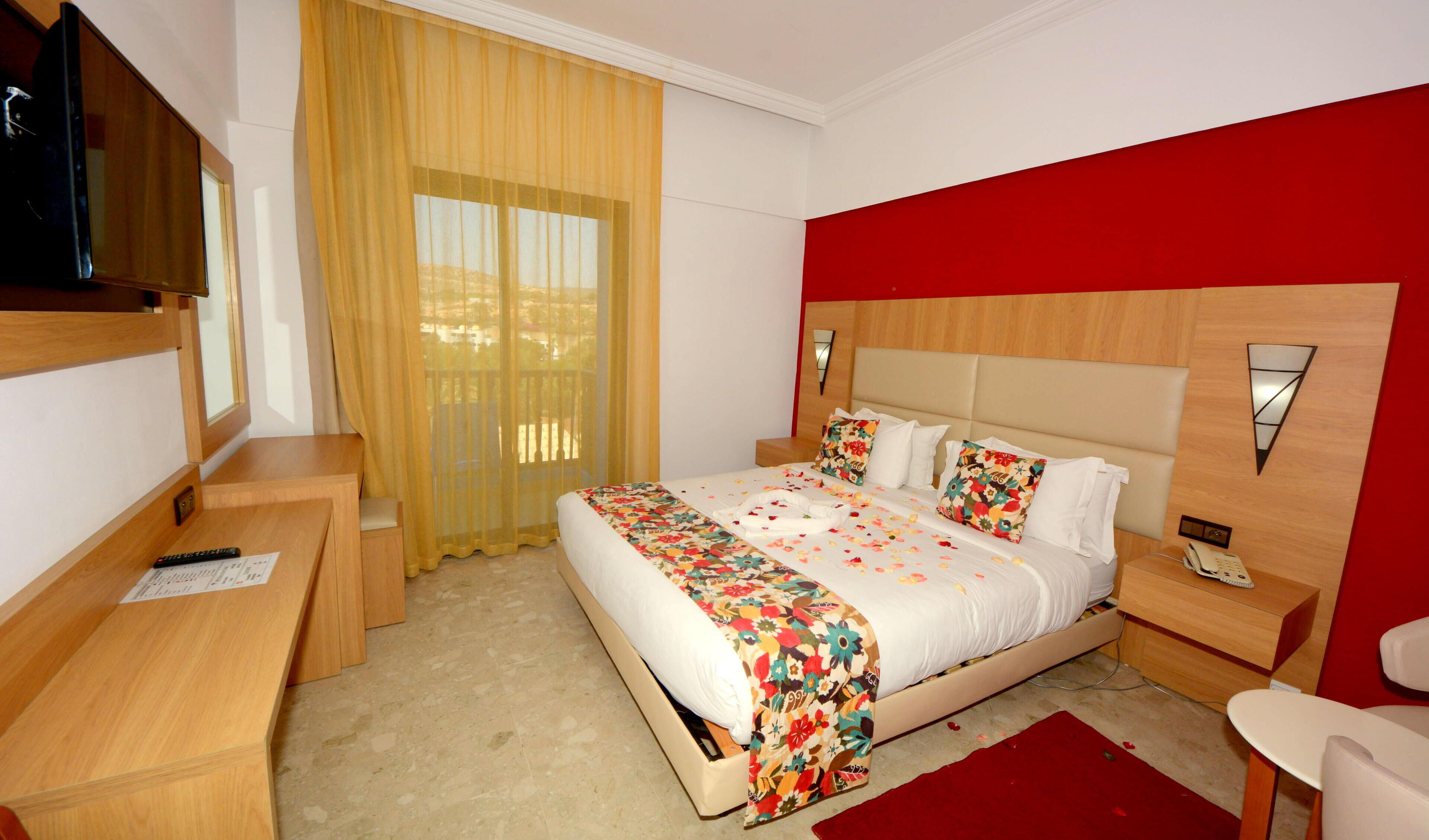 A hotel room with a bed, a TV, a desk, and a chair.