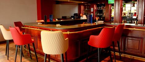 A bar area with a counter, bar stools, and a television screen.