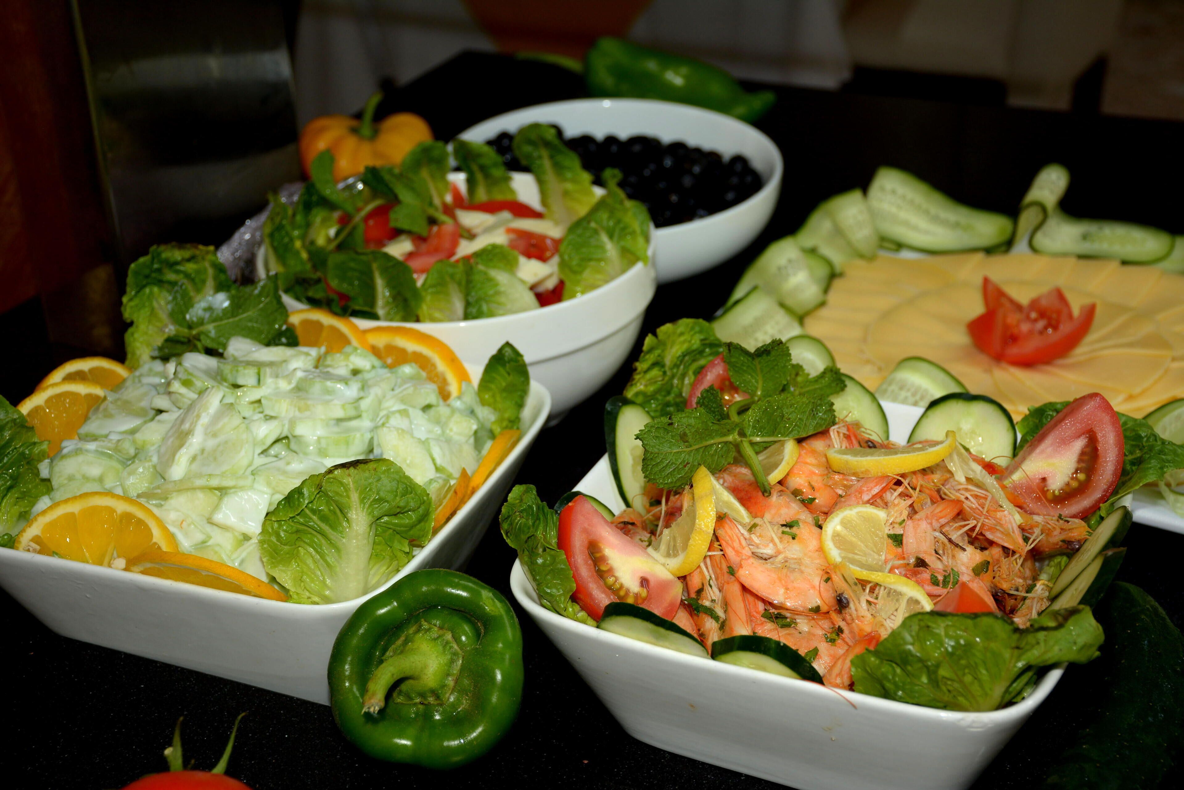 Three bowls of salad with various vegetables and fruits.