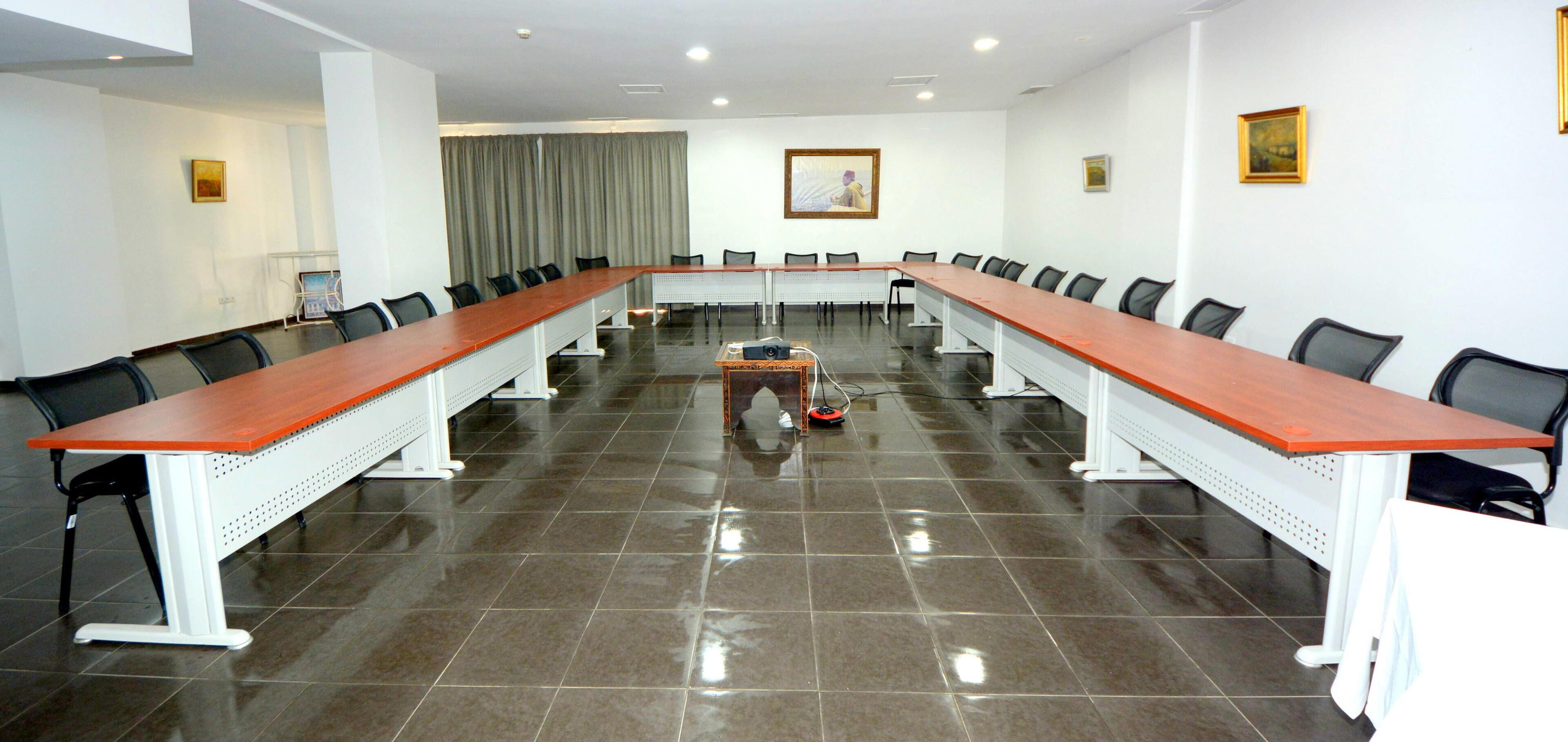 A conference room with a long table, chairs, and a projector.