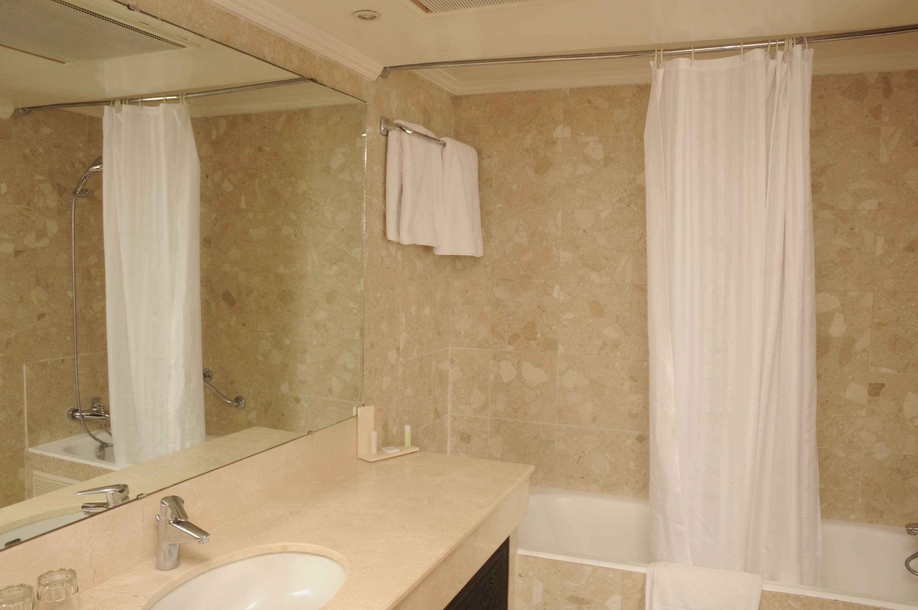 Un baño con lavamanos, espejo, cortina de ducha y bañera.