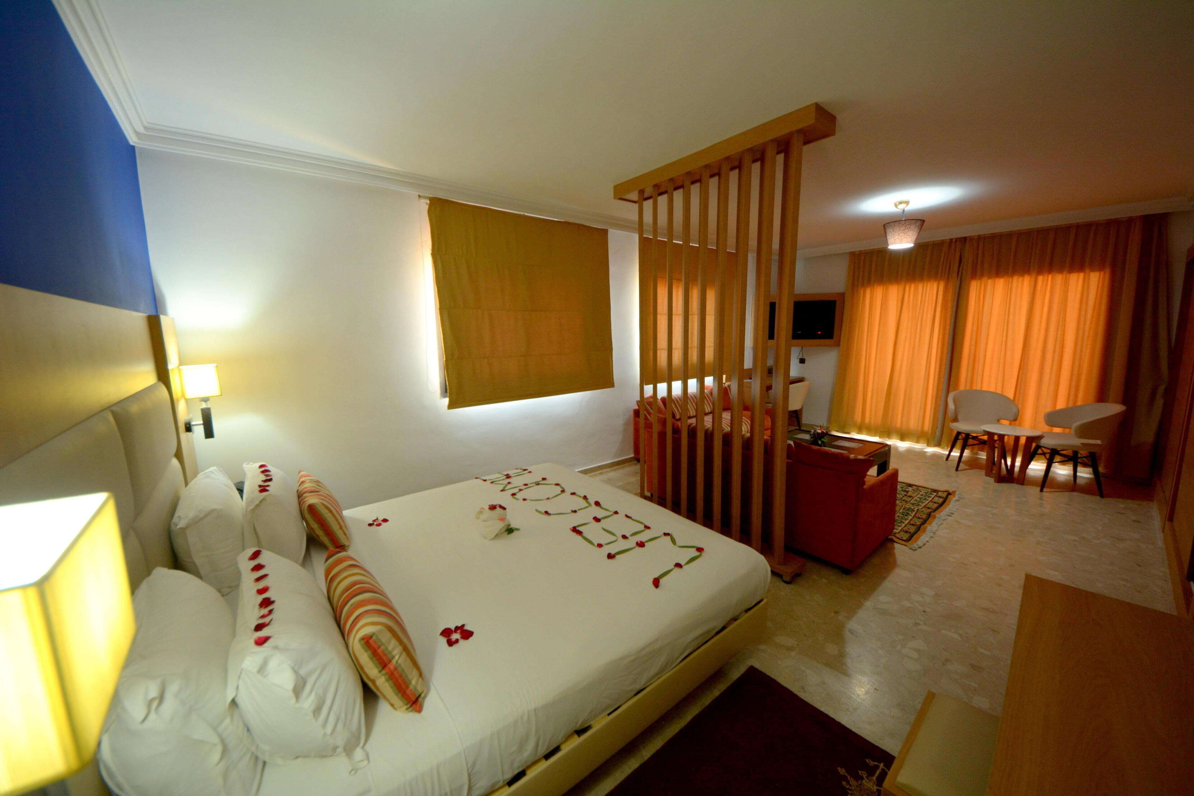 A hotel room with a bed, a desk, a chair, and a window with curtains.