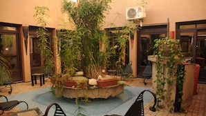 A courtyard with a central planter, seating area, and a wall-mounted air conditioning unit. - Oasis Hôtel & Spa (Agadir)