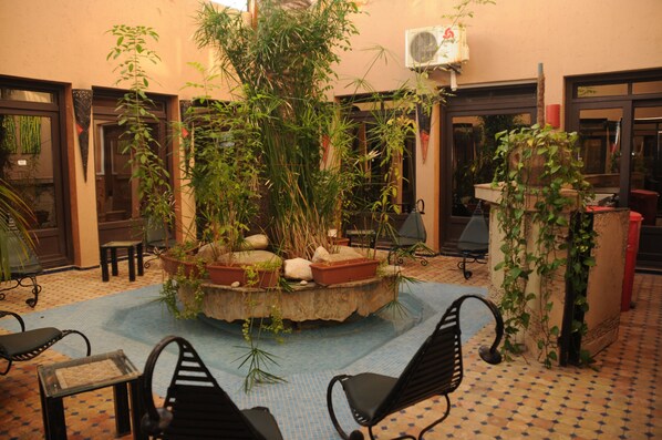 Une cour intérieure avec un jardin central, un espace aménagé pour s’asseoir et un climatiseur fixé au mur.