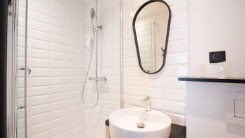 A modern bathroom with a glass-enclosed shower, a white sink, and a mirror.