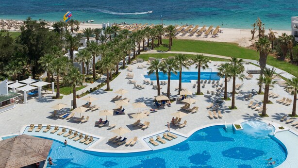Ein Resort mit großem Pool, Strand und Palmen.