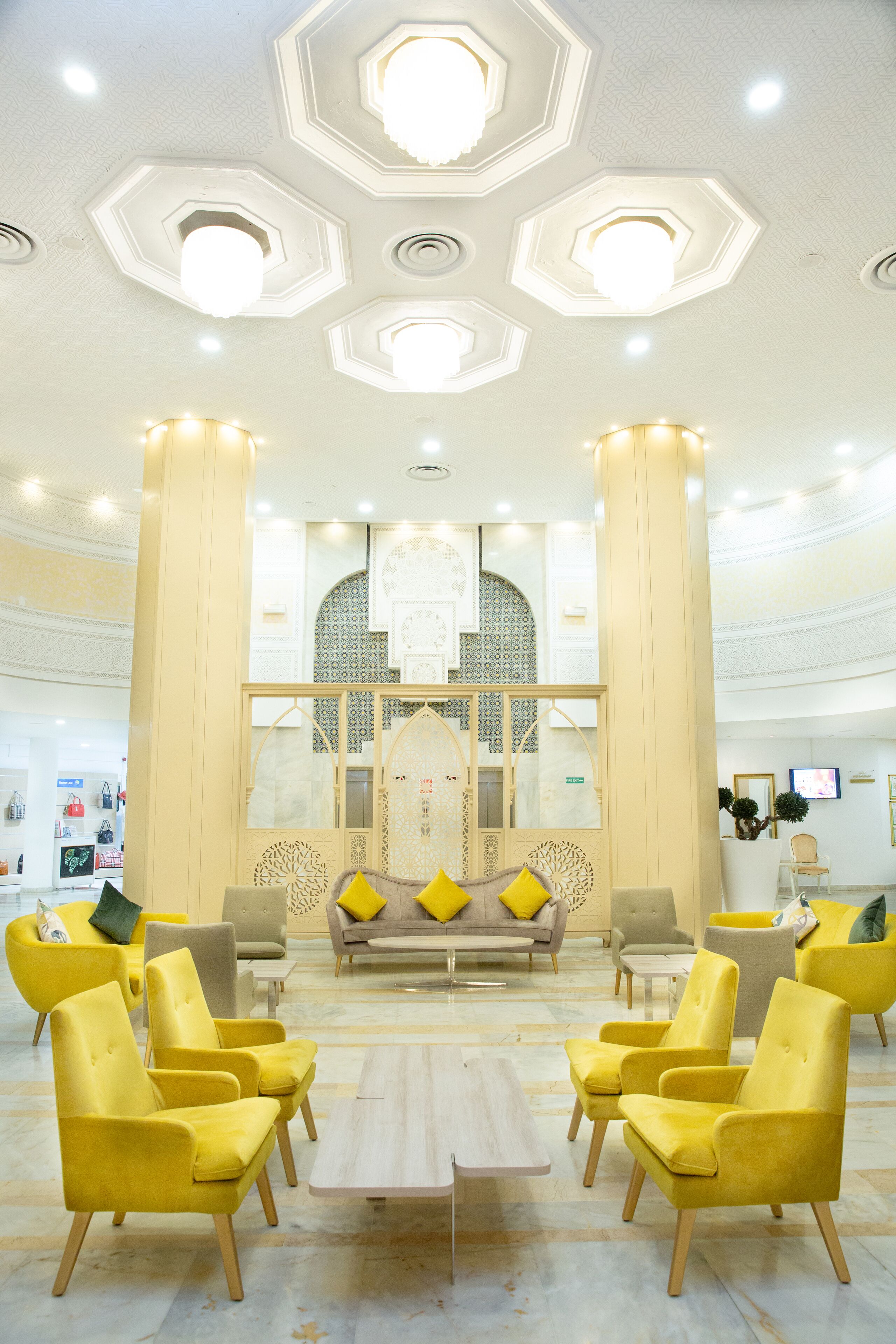 A spacious lobby with a central seating area, large columns, and a decorative ceiling.