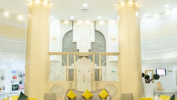 A spacious lobby with a central seating area, large columns, and a decorative ceiling.