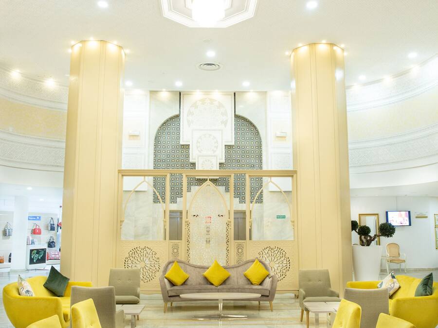 A spacious lobby with a central seating area, large columns, and a decorative ceiling.