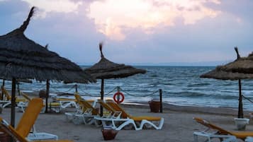 En privat strand, hvidt sand, liggestole, parasoller