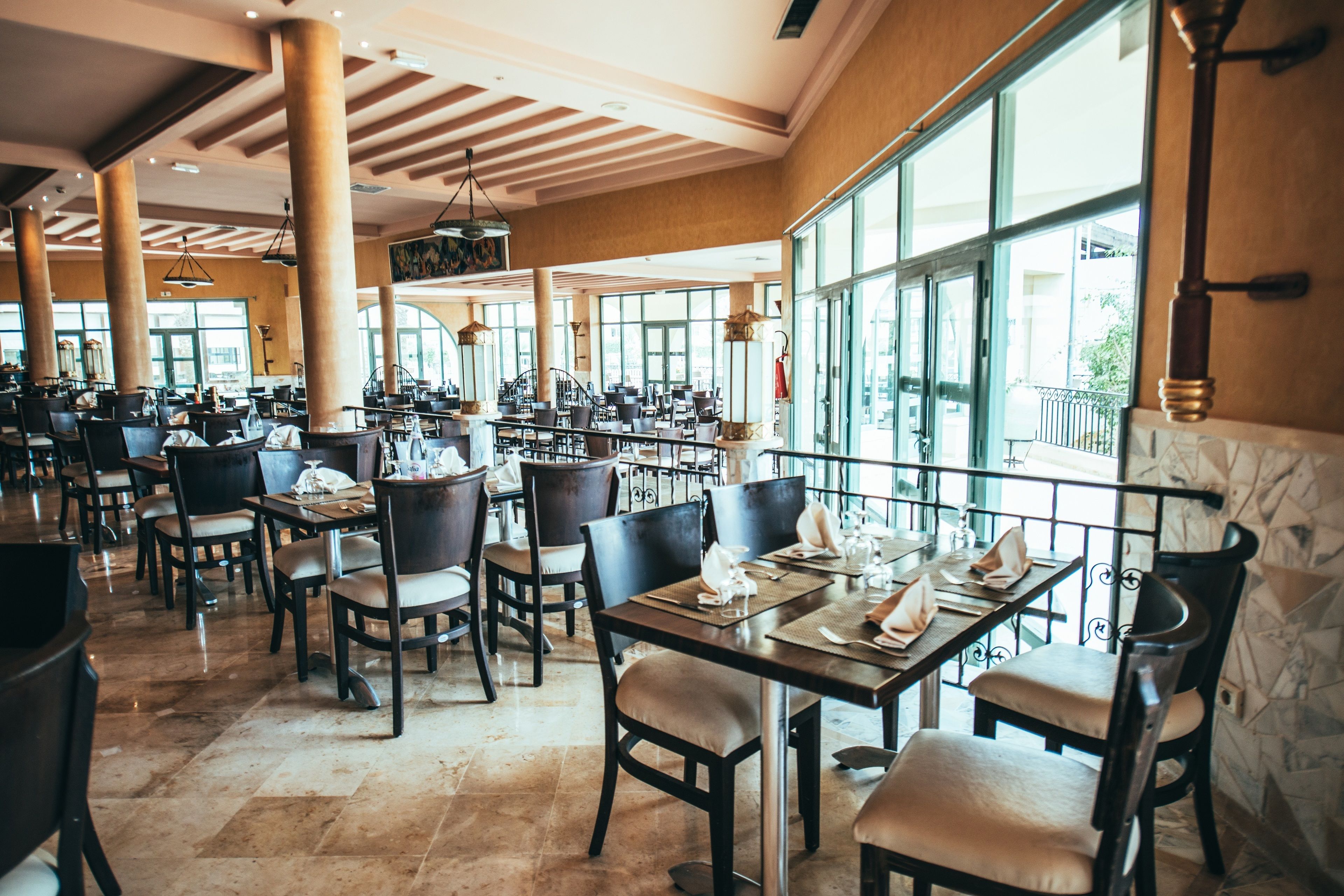 Un restaurant spacieux avec de hauts plafonds, de grandes fenêtres et différents types d’aménagements pour s’asseoir.