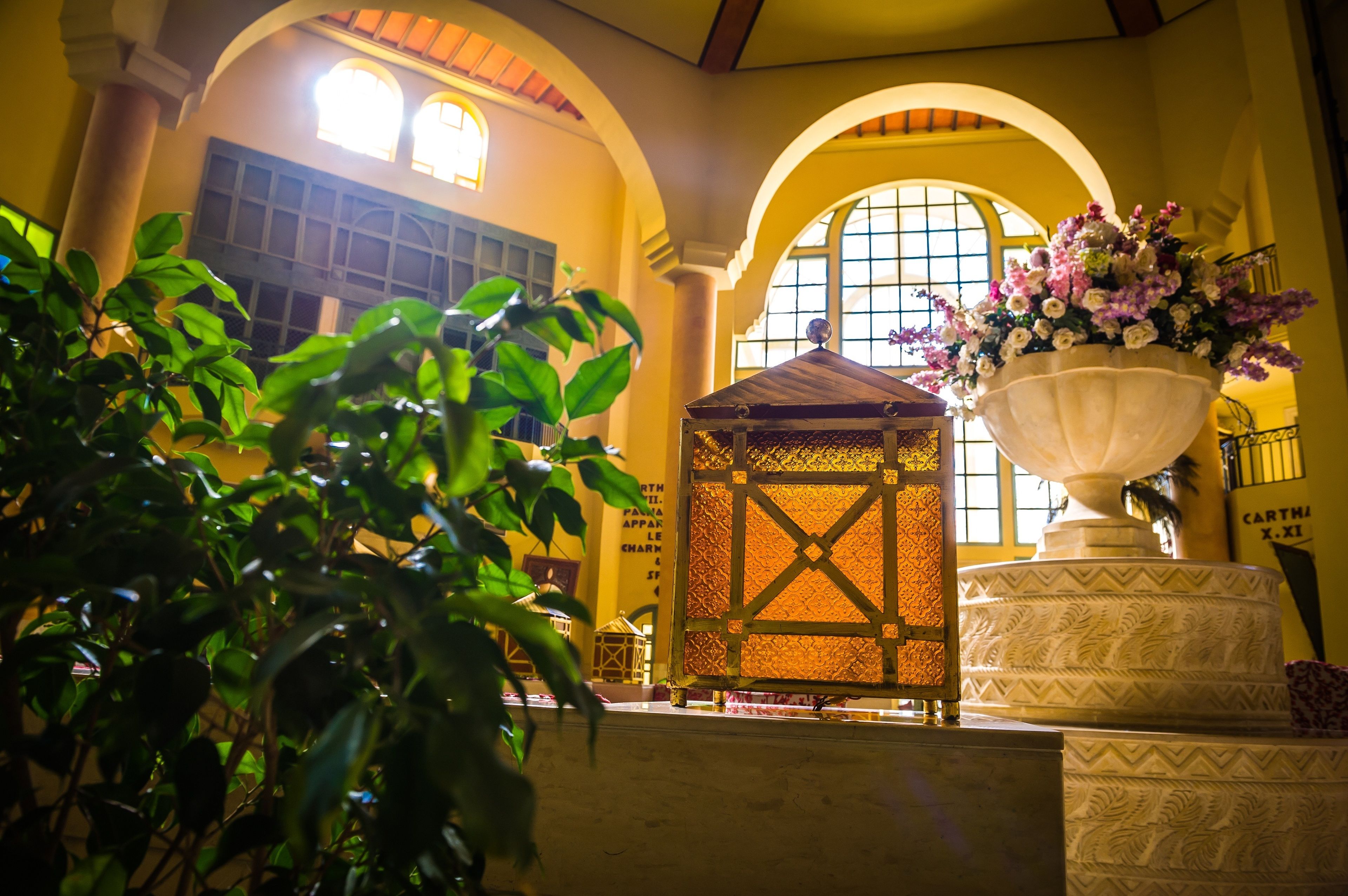 Ein Kircheninneres mit Bogenfenstern, einer Holzkonstruktion und einer großen Blumenkomposition.