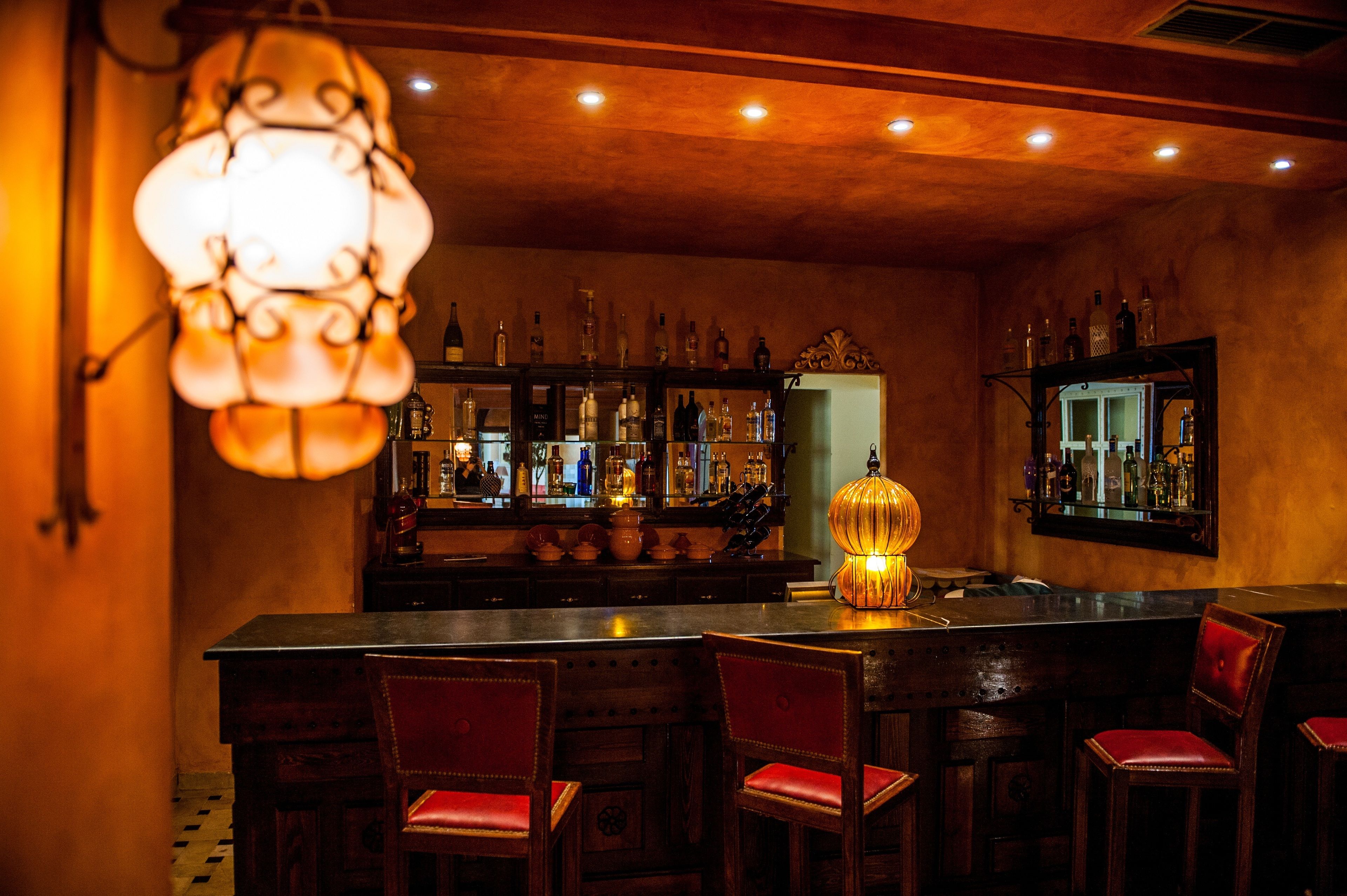 A bar area with wooden furniture, a bar counter, and shelves of bottles.