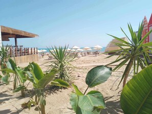 En privat strand, hvidt sand, liggestole, parasoller