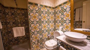 Un baño con lavamanos grande, inodoro y ducha. Las paredes están decoradas con un estampado floral de azulejos.