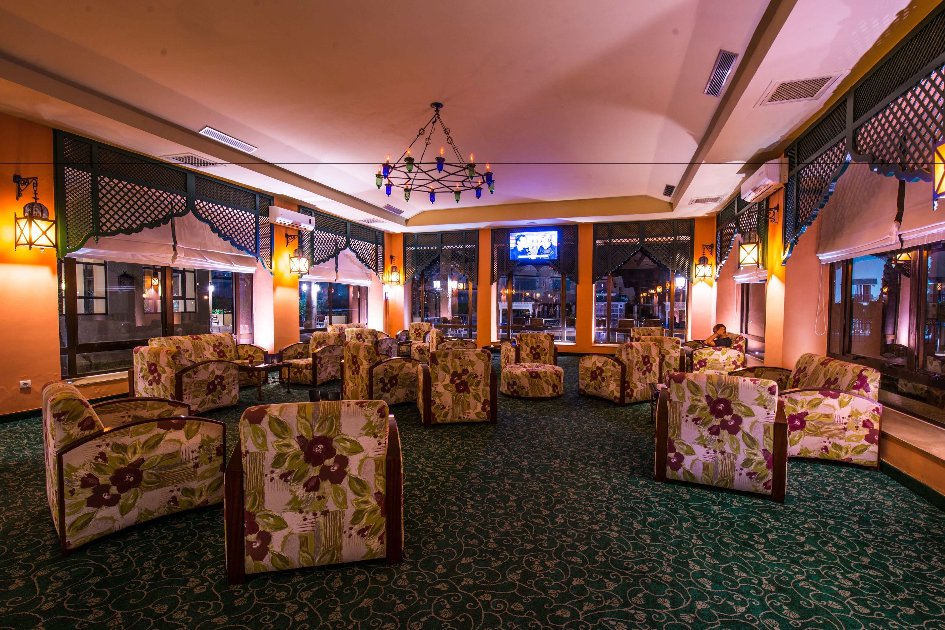 A hotel lobby with floral-patterned seating, a chandelier, and large windows.