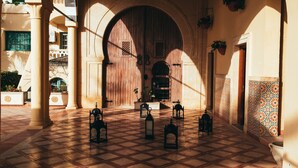 An arched entrance with a checkered floor, potted plants, and hanging planters. - Carthage Thalasso Resort (La Marsa)