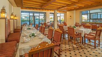Un restaurant avec de nombreuses tables dressées pour le service, doté de chaises à rayures et de tables en bois.