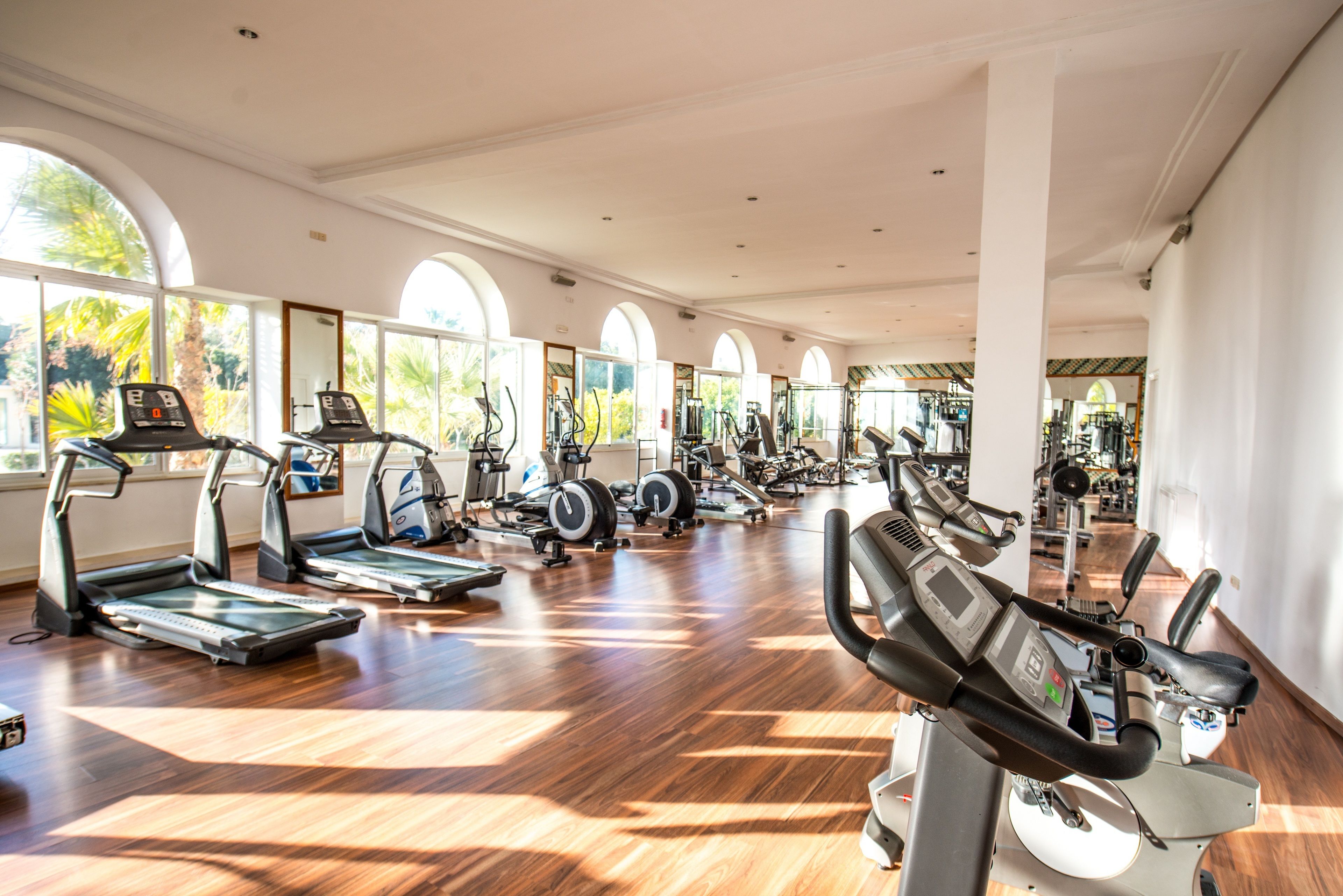 Ein geräumiges Fitnessstudio mit mehreren Laufbändern, Ergometer und Kraftgeräten.