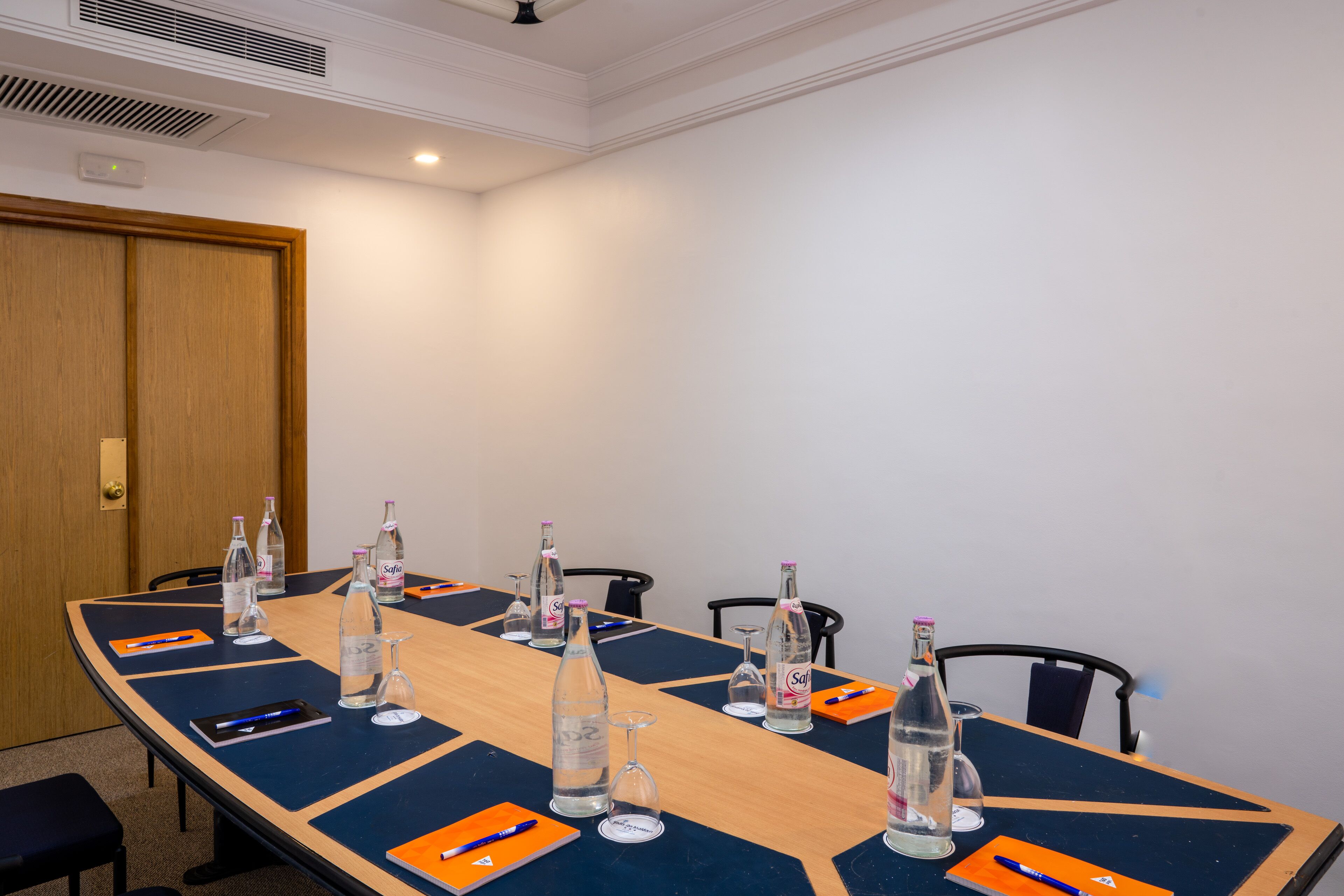 Ein Konferenzraum mit langem Tisch, Stühlen und Wasserflaschen.