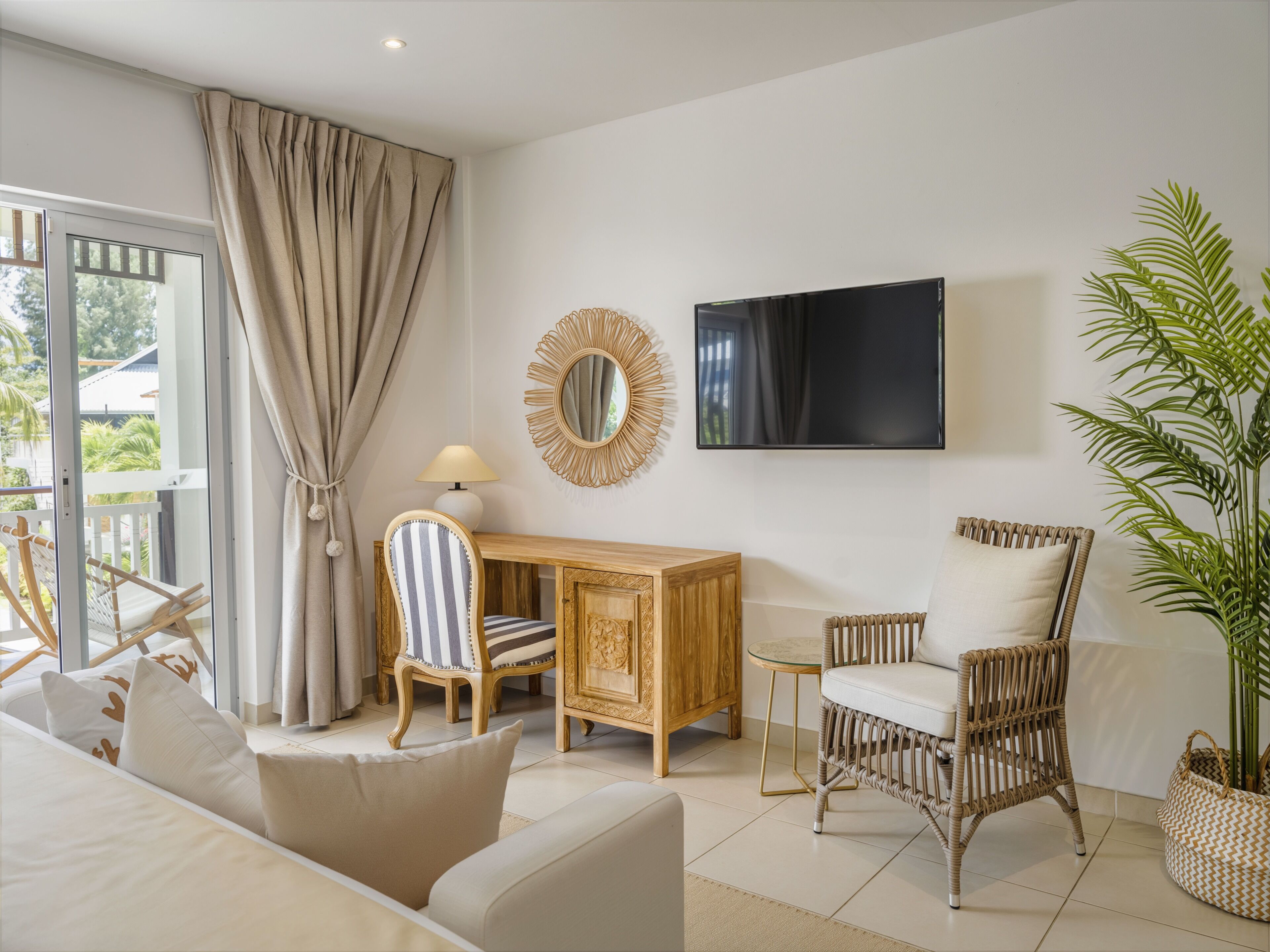 Ein Zimmer mit einer Couch, einem Sessel, einer Holzkabine, einem Fernseher und einer Pflanze.